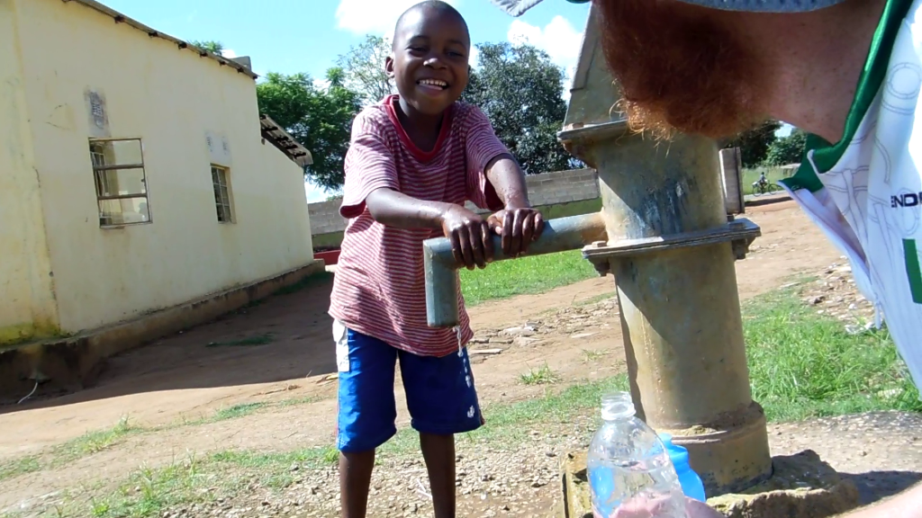 A kid helping me fill water bottles from a well
